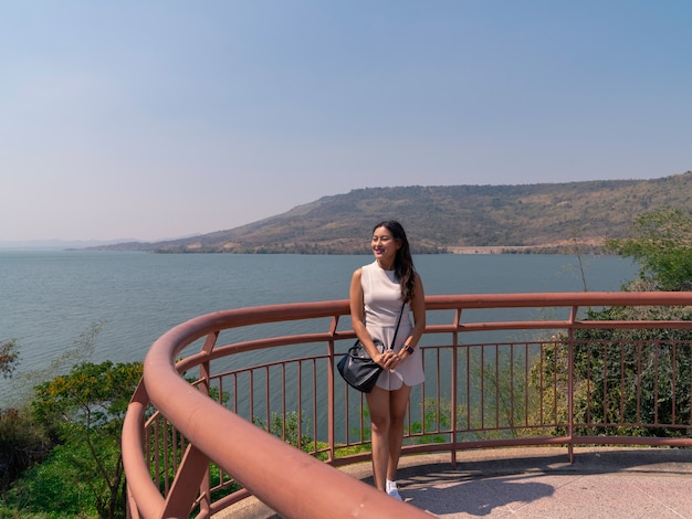 Happy asian woman tourist relax at Lamtakong dam view point terrace, travel destination in Nakhon Ratchasima, Thailand