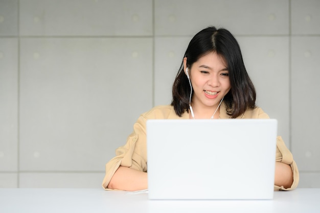 Happy Asian woman video conferrence working with laptop at home in office