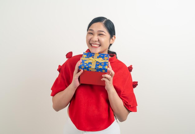 Happy Asian woman wearing red shirt with gift box on hand for Christmas festival