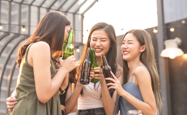 Happy asian women holding bottle of beer chat together.