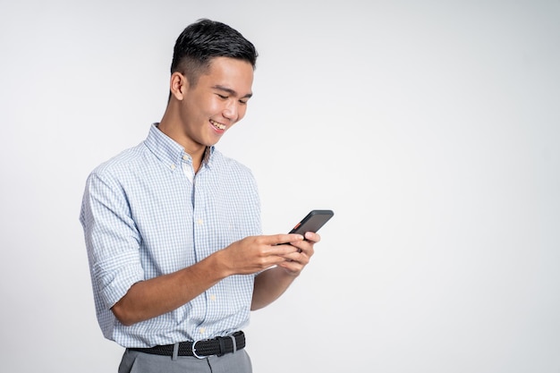 Happy asian young man looking at the screen of a mobile phone