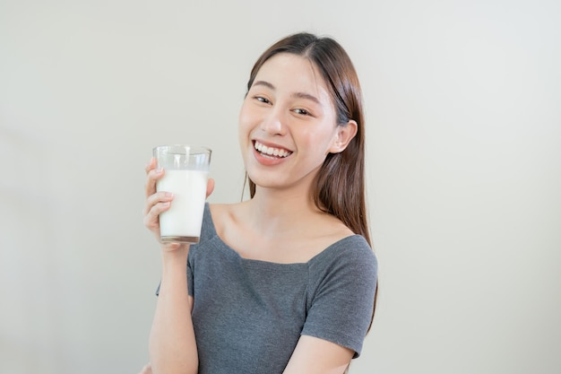 Happy asian young woman girl drinking a glass of white fresh warm or hot dairy milk for calcium vitamin wholesome good nutrition in morning lifestyle product healthy people Isolated background