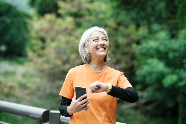 Happy athletic Senior woman checking her smartwatch in the park