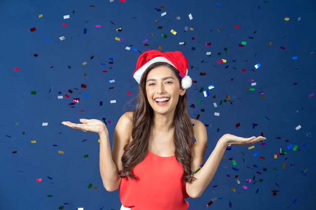 Happy attractive Asian woman celebrate party with multi color confetti falling on blue color background