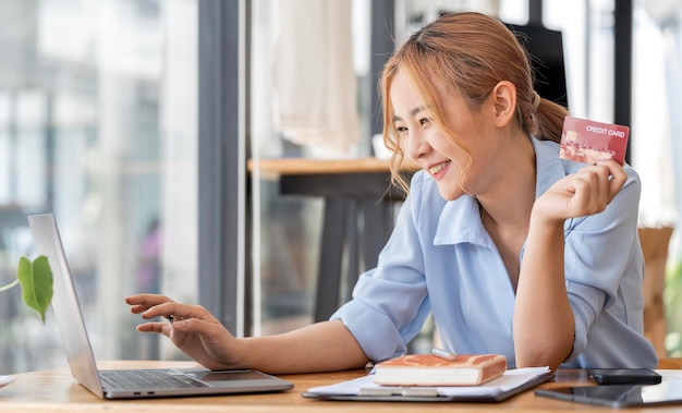 Happy attractive Asian woman using laptop and creditcard for online shopping onlne banking concept