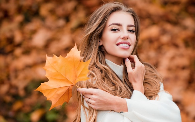 Happy autumn woman having fun with leaves outdoor in park