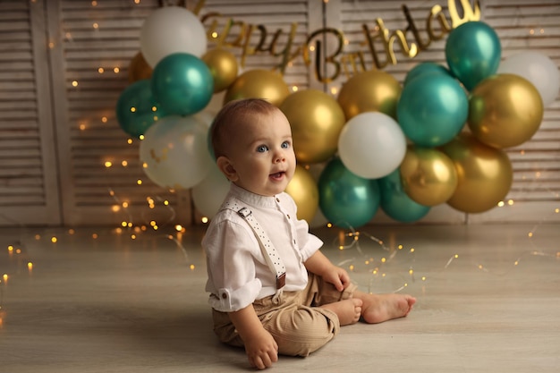 Happy baby on the background of balloons with garlands and the inscription happy birthday