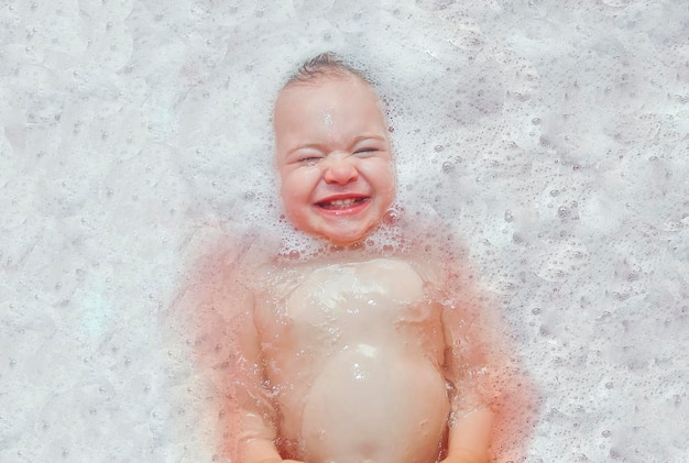 Happy baby girl in the bath swimming in the foam Baby shower