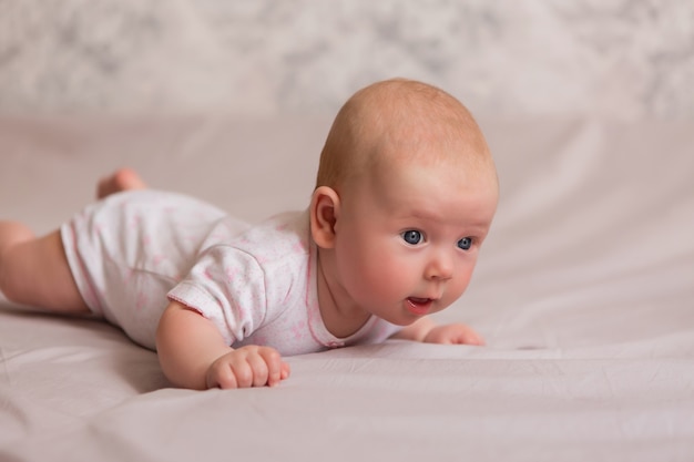 Happy baby girl lying on bed