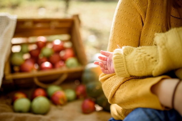 Happy baby girl with a basket with apples outdoor in the autumn park