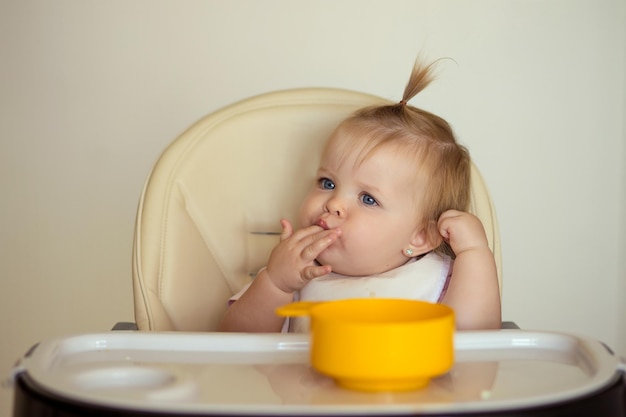 happy baby is sitting on a chair and getting ready for feeding