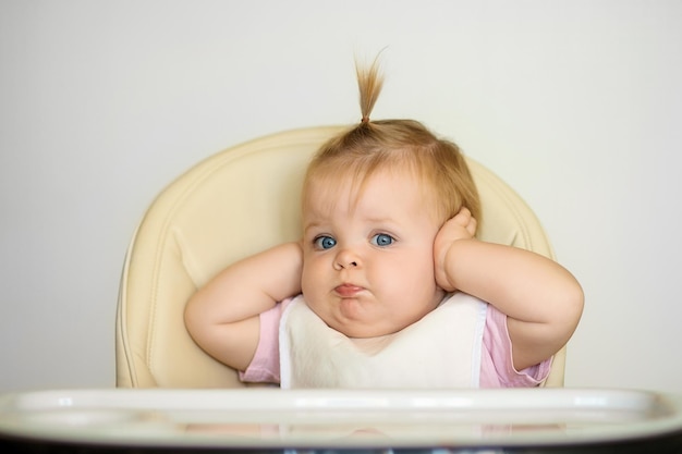 happy baby is sitting on a chair and getting ready for feeding