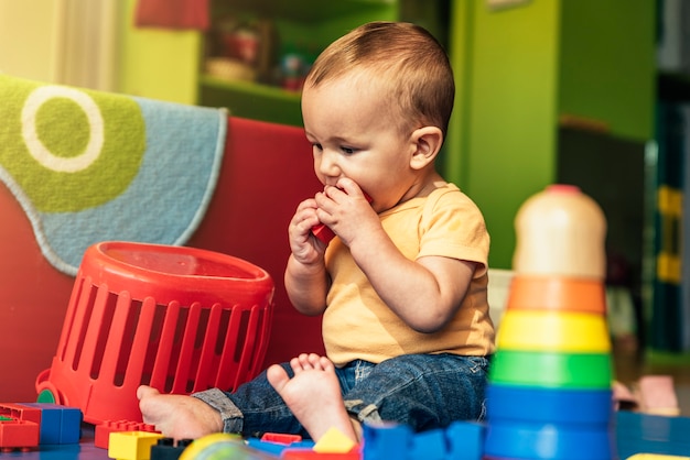 Happy baby playing with toy blocks in the kindergarten.