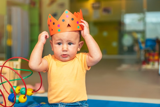 Happy baby playing with toy blocks in the kindergarten.