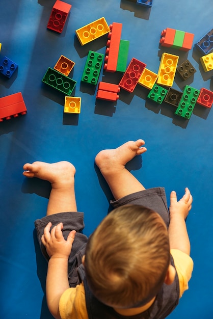 Happy baby playing with toy blocks in the kindergarten.