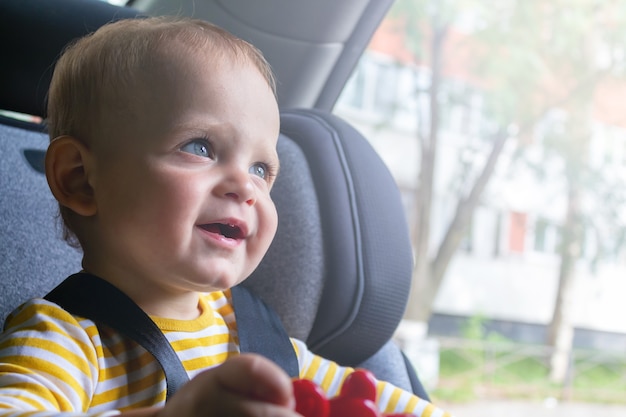 Happy baby sitting in car seat playing