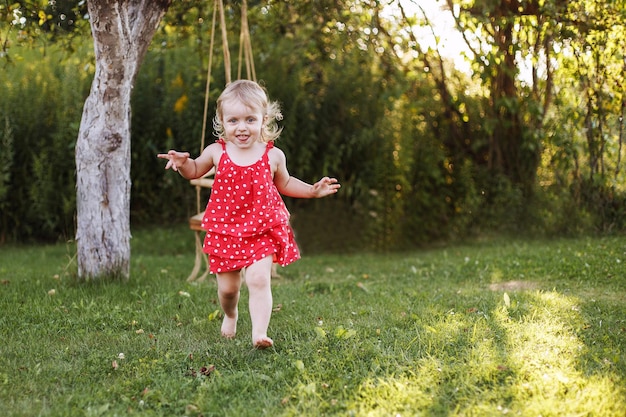 Happy baby smiling a little girl running in the garden at sunset outdoor barefoot