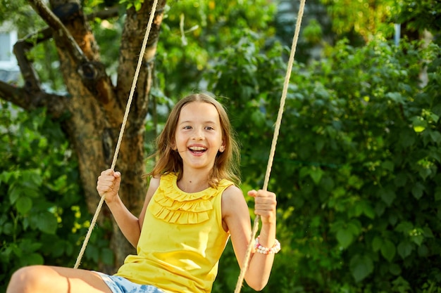 Happy barefoot laughing child girl swinging on a swing in sunset summer day