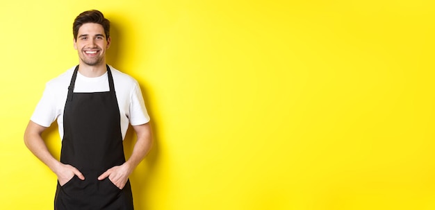 Happy barista in black apron looking at camera coffee shop owner wearing cafe uniform and smiling st