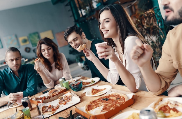 Happy to be around. Group of young people in casual wear talking and smiling while having a dinner party indoors