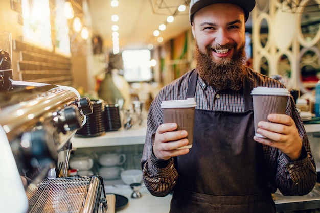 Happy bearded barista holding smiles on camera