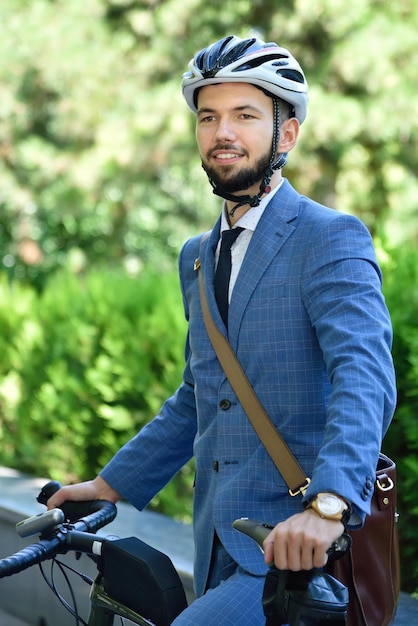 Happy bearded businessman in helmet with bicycle