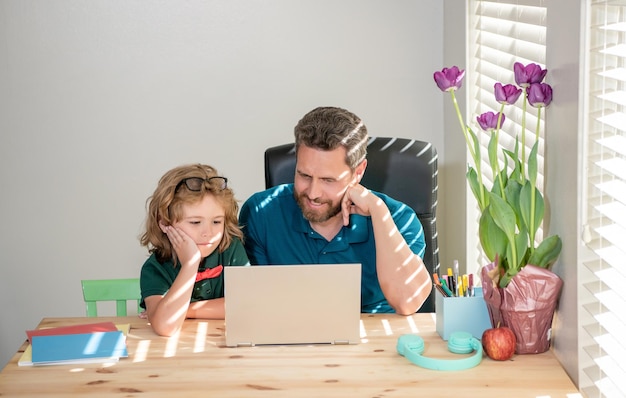 Happy bearded dad or school private tutor teaching boy son with modern laptop knowledge