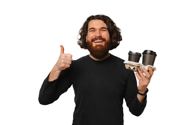 Photo happy bearded man is holding two take away coffee cups and a thumb up