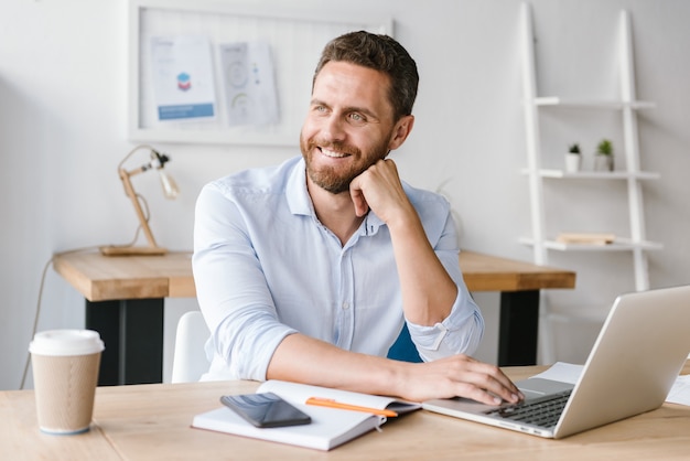 Happy bearded man sitting in office working