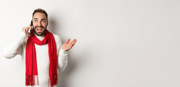 Photo happy bearded man wishing merry christmas on phone calling someone and talking standing in sweater w