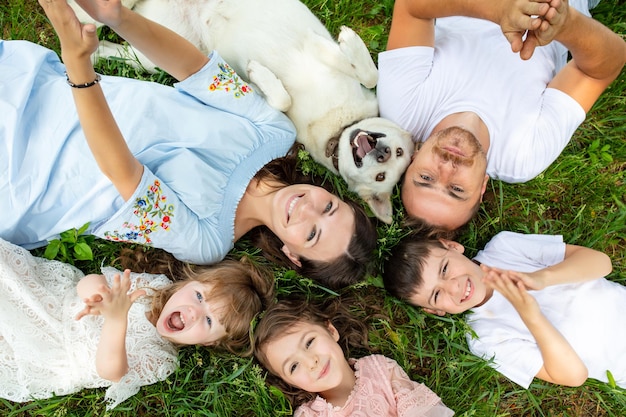 Happy beautiful big family together mother father children and dog lying on the grass top view