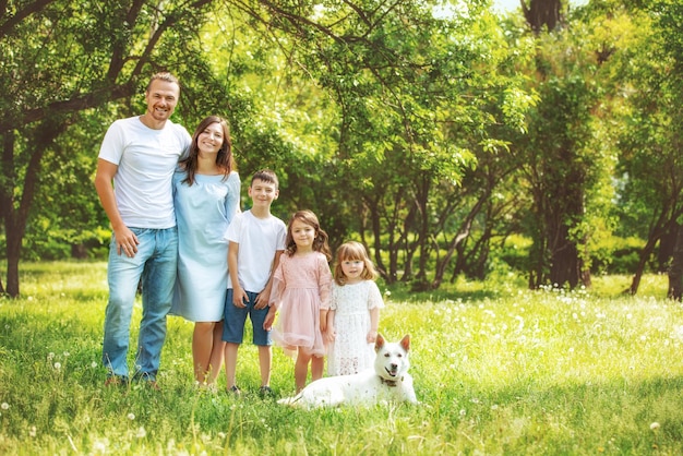 Happy beautiful big family together mother father children and dog walking on a Sunny summer day