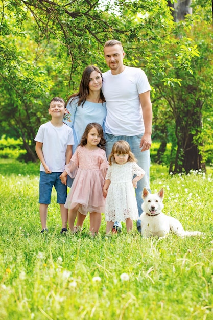 Happy beautiful big family together mother father children and dog walking on a Sunny summer day