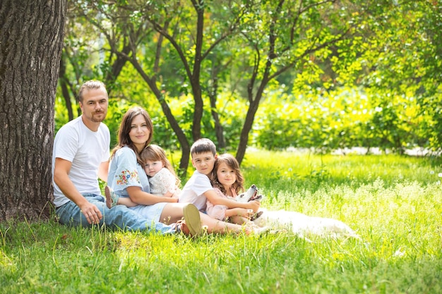 Happy beautiful big family together mother father children and dog walking on a Sunny summer day