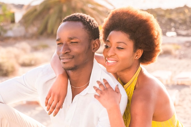 happy beautiful black race african couple in love or friendship stay together walking hugged with big smilies under the sunlight of the summer in vacation or lifestyle in their city