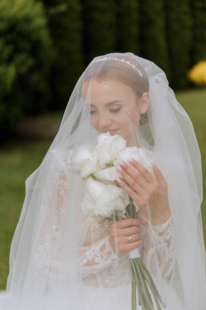 Happy beautiful bride under veil closeup Beautiful bride shows makeup and hairstyle