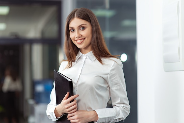 Happy Beautiful Business Woman in Office Hall with documents in hand.