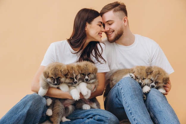 Photo happy beautiful couple in love or volunteers caring and playing with little funny akita inu puppies