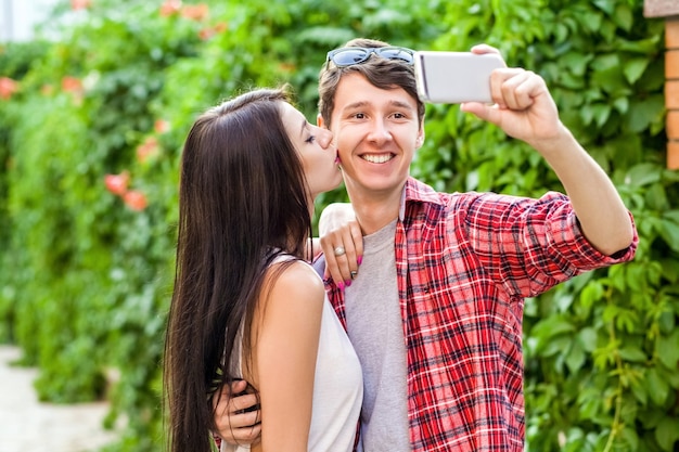 Happy beautiful couple taking a selfie on a mobile phone huging and have a fun together