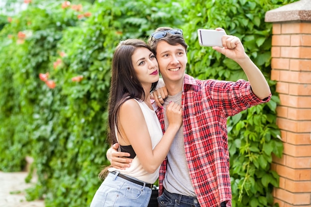 Happy beautiful couple taking a selfie on a mobile phone huging and have a fun together