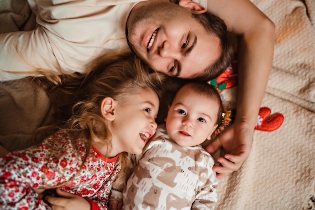 Happy beautiful family laughing lying on the carpet new year mood daddy playing with children