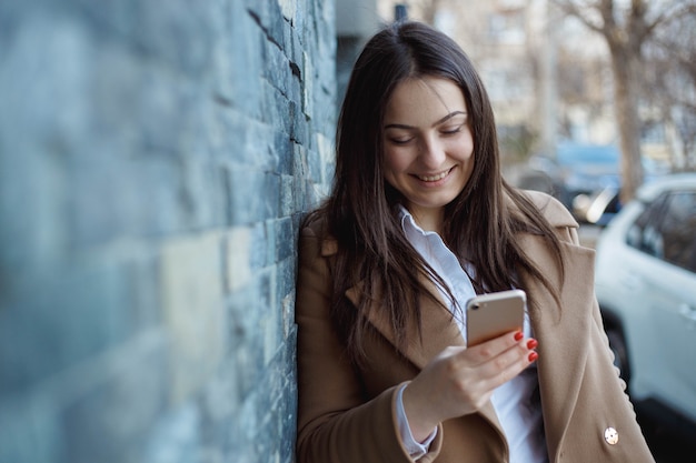 Happy beautiful girl using smart phone in the city