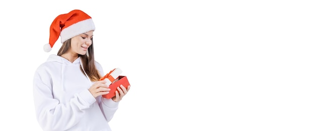 Happy beautiful girl with red santa claus hat holds gift box in white