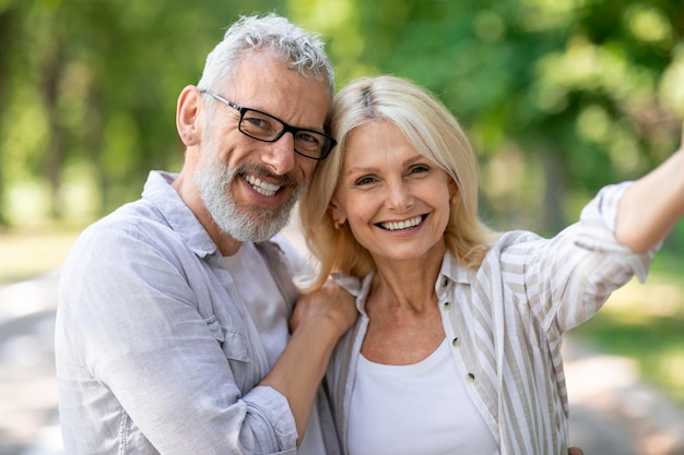 Happy beautiful mature couple posing for selfie together outdoors