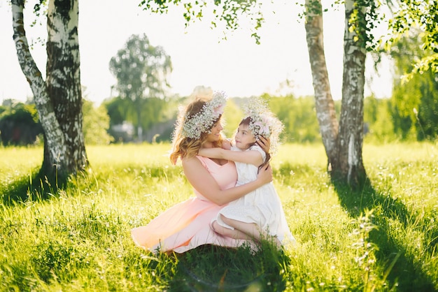 Happy beautiful mother with a daughter of Caucasian appearance hugging in the meadow