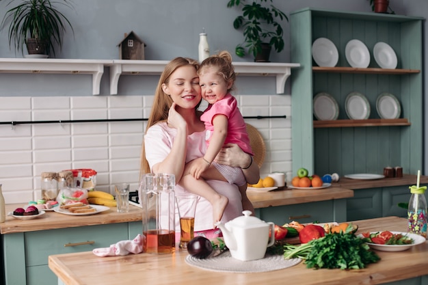 Happy beautiful mother with daughter in morning kitchen