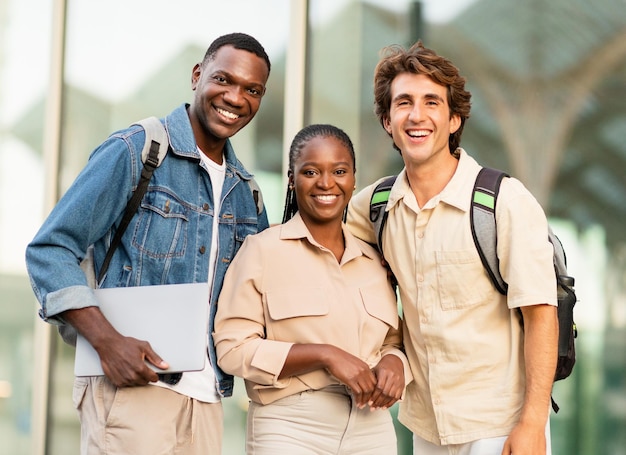 Happy beautiful multicultural group of students posing by university