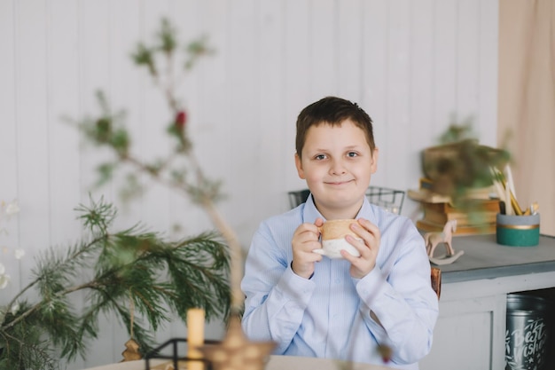 Happy beautiful portrait of a smiling caucasian child boy on the background of a Christmas tree in a home interior and festive atmosphere