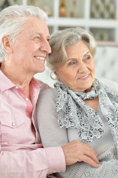 Happy beautiful senior couple sitting on couch at home