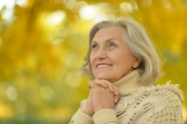 Happy beautiful senior woman in the autumn park